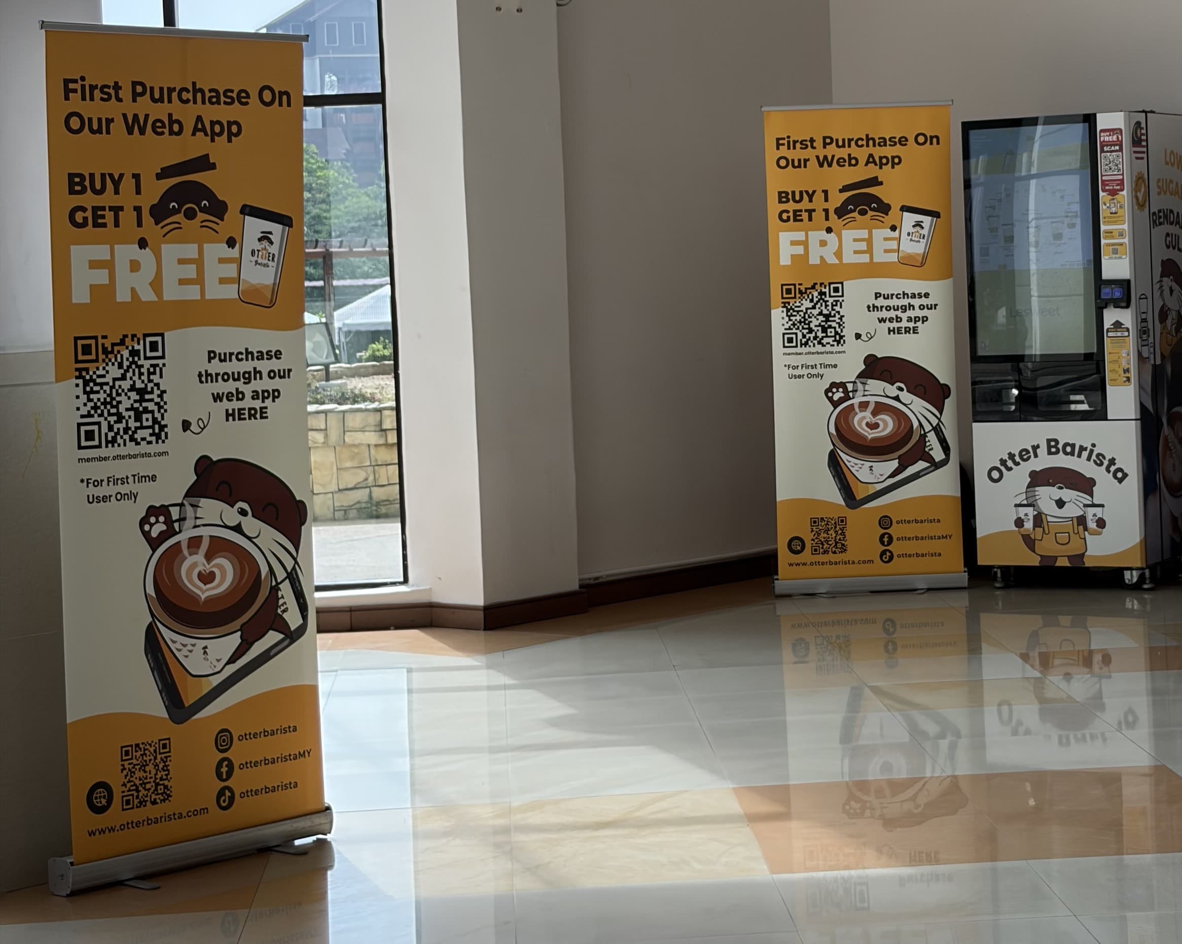 Sleek Otter robotic barista dispensing espresso drinks at a corporate event setup in a Kuala Lumpur office lobby or convention space.