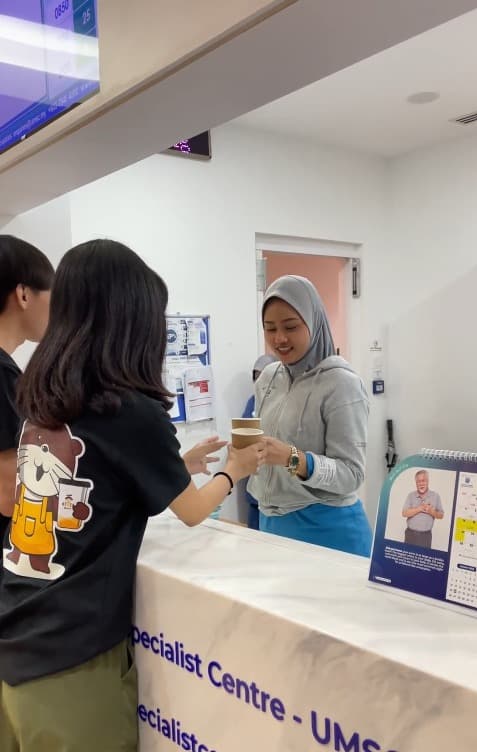 Otter robotic barista dispensing espresso to a nurse in hospital scrubs during a night shift break at a ward station.