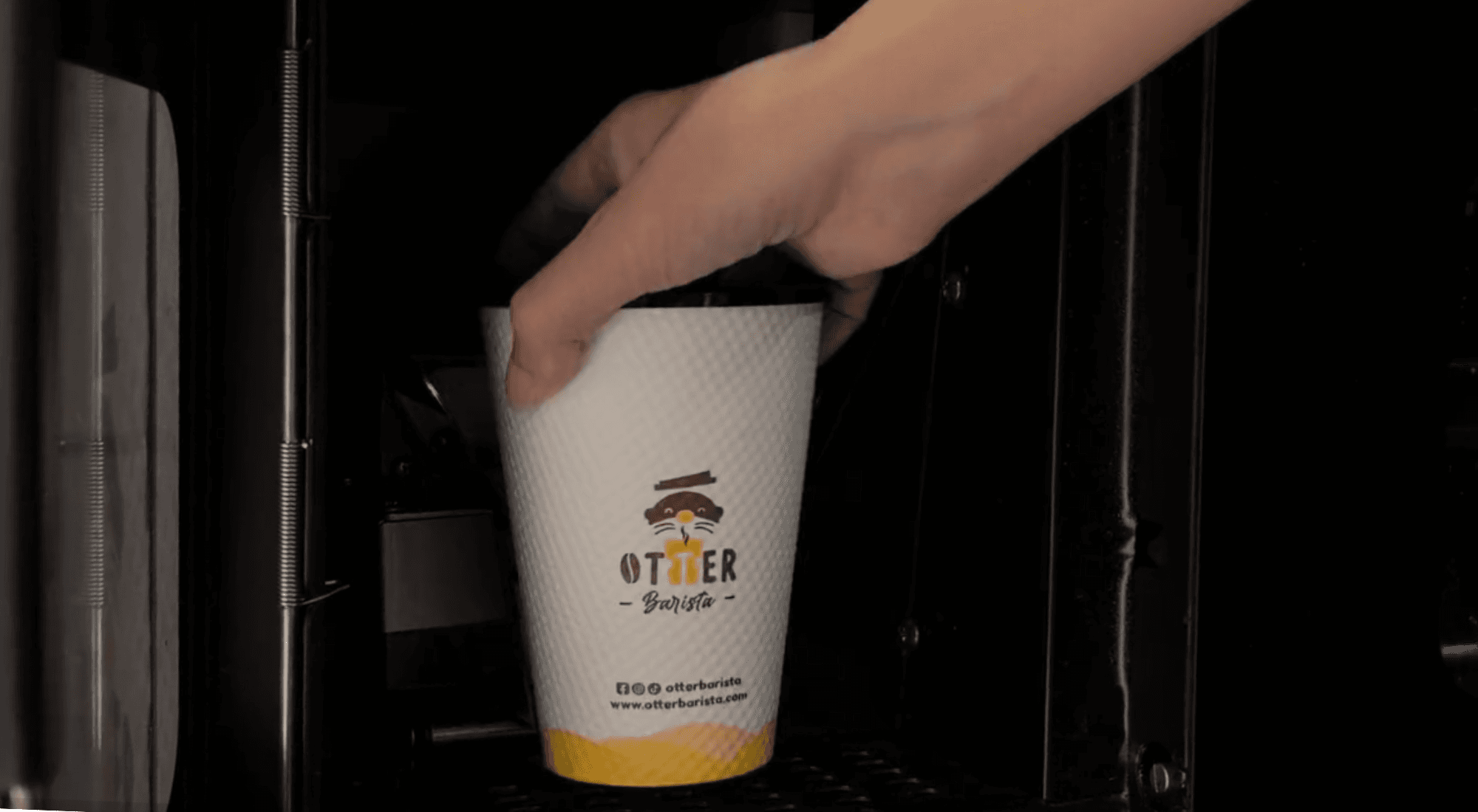 Sleek Otter robotic barista dispensing specialty coffee into a waiting cup at a modern office pantry station during morning break.