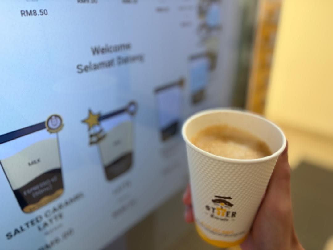 Close-up of an Otter robotic barista dispensing a fresh espresso into a ceramic cup in a corporate office pantry during morning break.