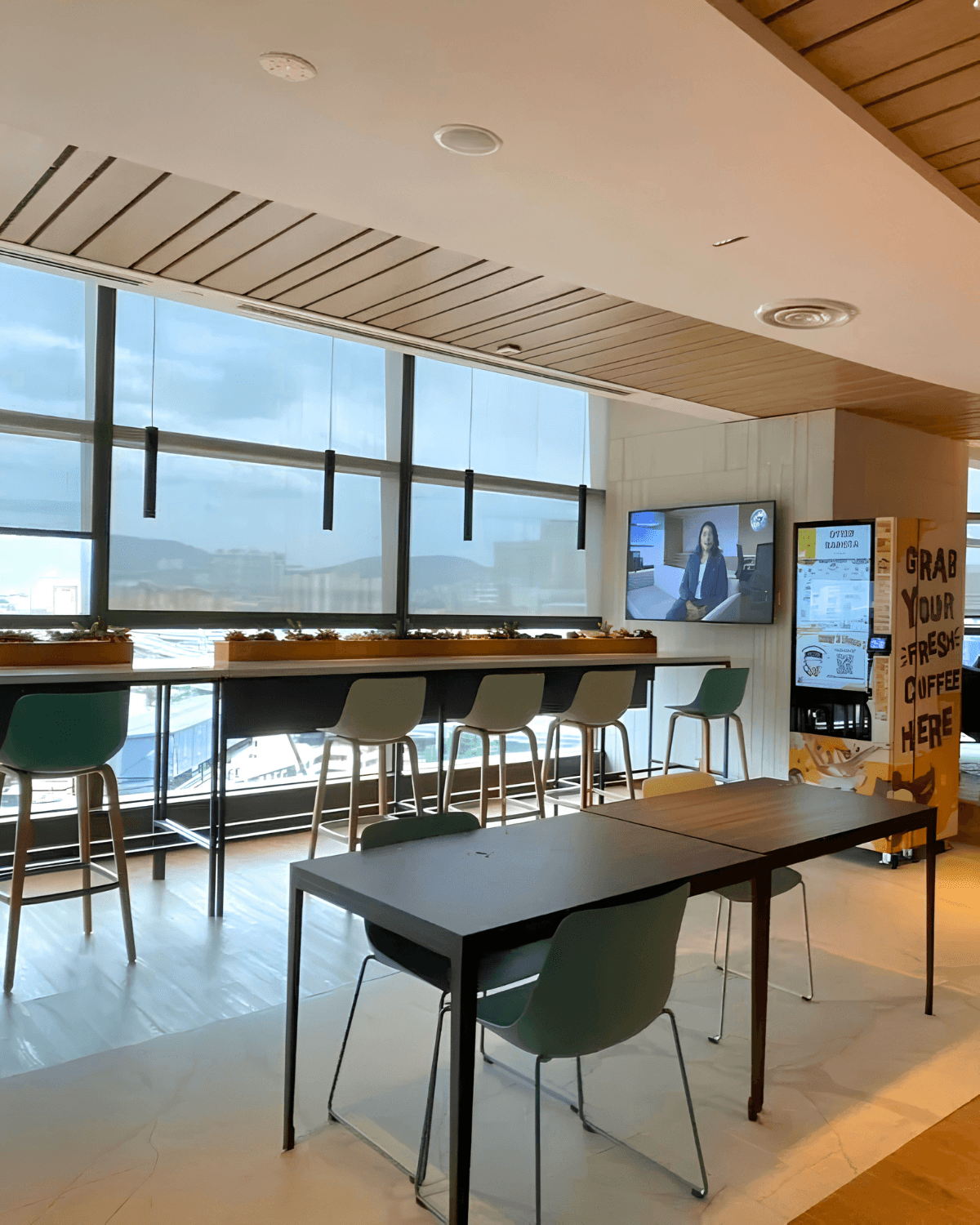 Sleek Otter robotic barista dispensing a cappuccino to an office worker at their desk during morning break in a modern Klang Valley corporate building.