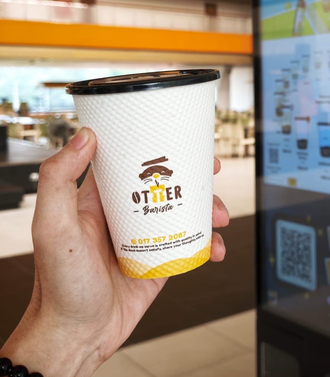 Sleek Otter robotic barista dispensing espresso into a ceramic cup inside a modern office pantry during morning break rush.